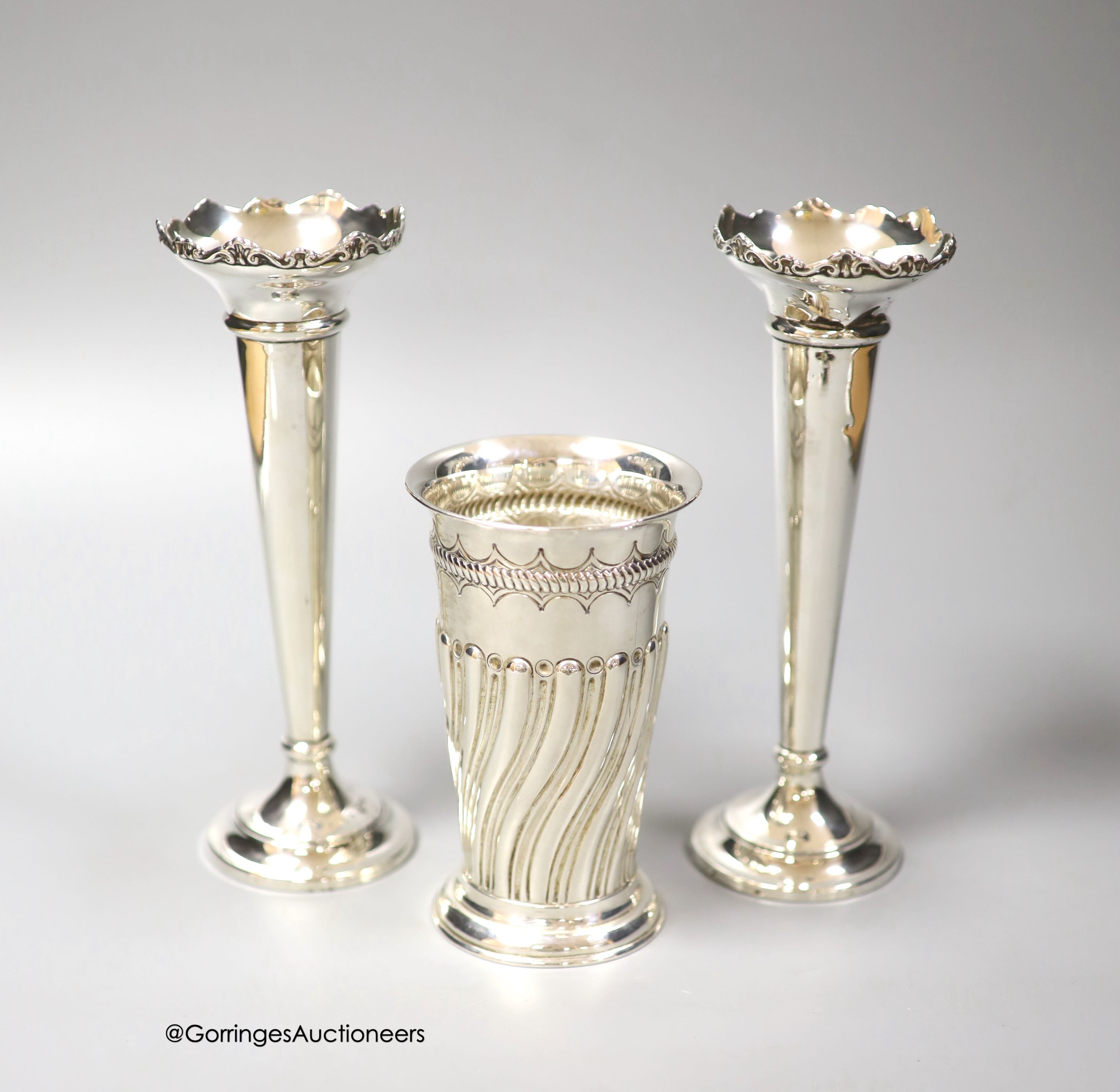 A late Victorian wrythened fluted silver vase, 13cm, 153 grams and a pair of later silver spill vases, 18.8cm, weighted.